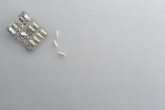 plaquette de m&eacute;dicament ouverte et g&eacute;lules sur fond blanc 