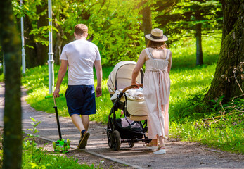 A married couple rolls a baby stroller in a city Park
