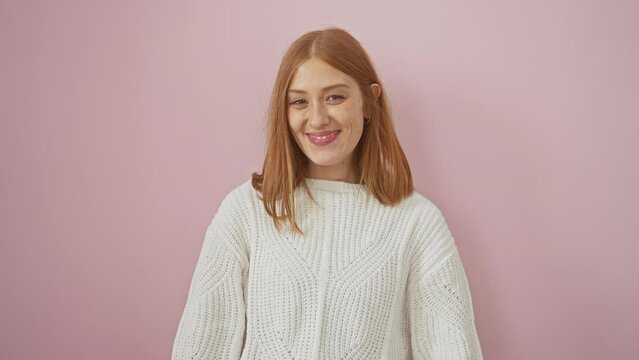 Crazy fun as young redhead woman makes hilarious fish face! cheerful expression, sweater-wearing, standing over pink isolated background.