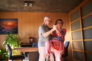 Senior couple dancing in the living room. Retired couple enjoying free time together at home