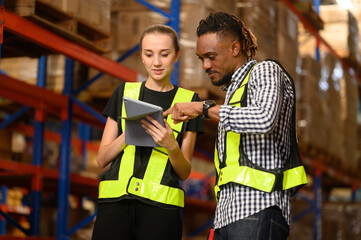 Retail Warehouse full of Shelves with Goods in Cardboard Boxes, Male and Female Supervisors Use Digital Tablet and Look For a Right Shelf. Forklift Working in Logistics Storehouse