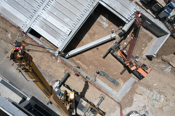 construction site with 2 crane trucks with operator taken to lift a large reinforced concrete beamdefault