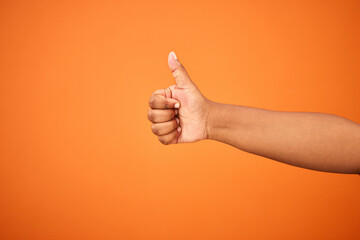 Thumbs up, hand and person with arm on orange background for thank you or confirm with gesture or...