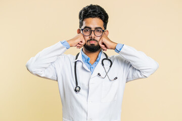 Indian young doctor cardiologist man feeling hopelessness and loneliness, nervous breakdown, loses, bad fortune, loss, unlucky news, fail. Arabian apothecary pharmacy guy isolated on beige background