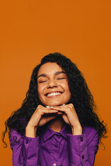 Vibrant smiling woman with curly hair on orange background