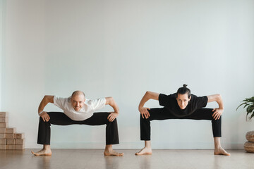 two young athletes practice yoga in the gym. Joint training, indoors, studio. The concept of a...