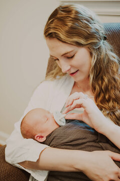 Young mom holding newborn sitting in cahir