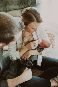 Mom and dad looking at new born baby cradled in moms arms