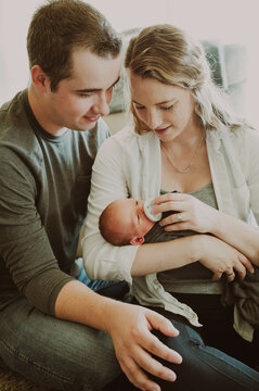mom and dad smiling at newborn baby in moms arms