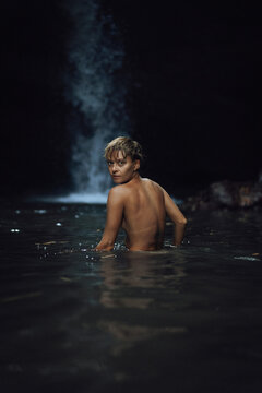 Young naked woman swims in a waterfall in the jungle.