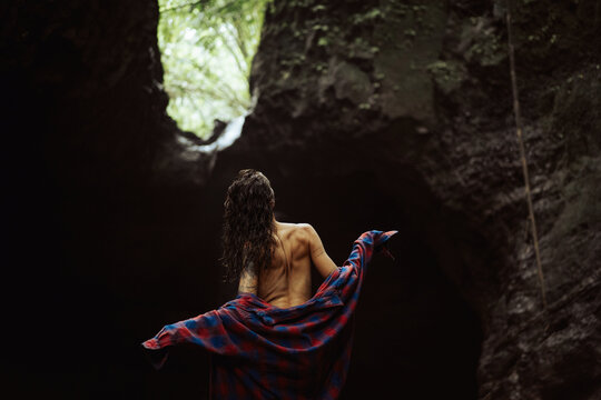 A young woman puts on clothes after swimming in a waterfall.