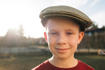 boy stood outside at sunset with a flat cap