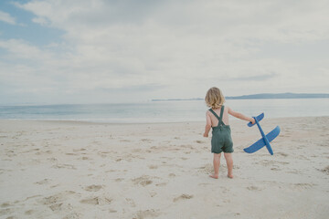 Child on beach in Summer with blue toy airplane