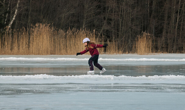 girl ice skating on a frozen lake by the forest in Sweden