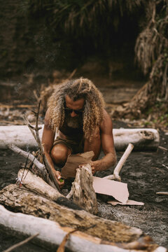 Man makes a campfire for a picnic on the beach by the ocean.