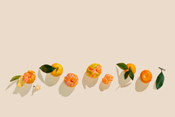 Fresh juicy orange yellow tangerines as minimal flat lay, Sweet Citrus fruits with green leaves on beige background. Top view of still life layout of mandarin oranges, above frame, copy space