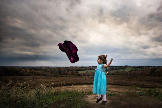 Little girl playing super hero outdoors in summer
