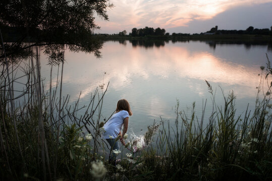 Young girl splashing water in beautiful lake at sunset