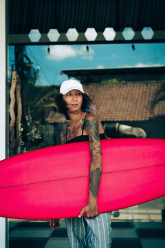 Portrait of young happy stylish woman with surfboard.
