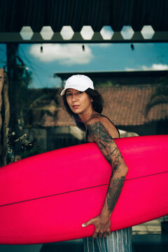 Portrait of young happy stylish woman with surfboard.