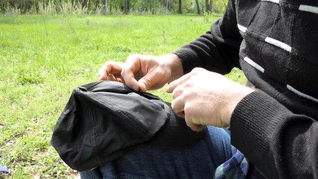A man repairing his baseball cap