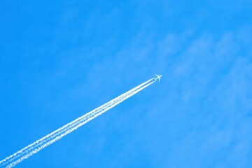 Airplane with contrails in the blue sky.