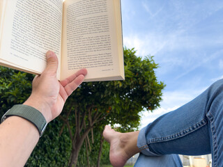 Man lying down and reading a book under the blue sky