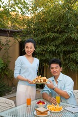 Husband and wife have breakfast in the yard