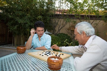Father and son in the yard to play chess