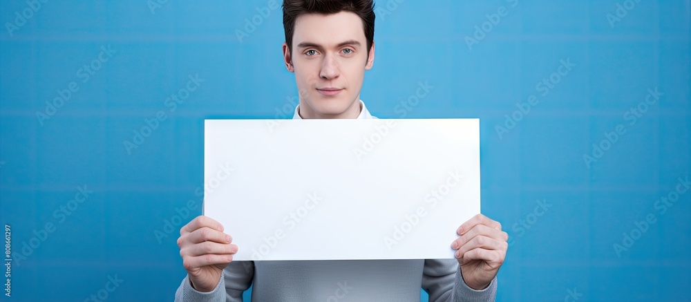 Poster on a blue background a young man is seen holding a sign with empty space for text or images. copy sp