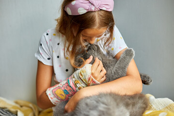 Teen girl with a broken arm orthopedic cast play with cat