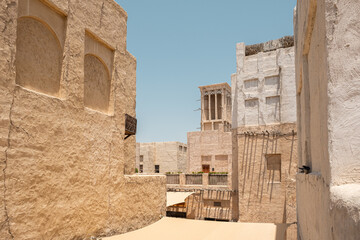 House in traditional Arabic architecture with wind tower. Traditional Arabic style building with windcatcher tower and palm leaves thatched roof. Old Dubai, UAE. View of rooftops of old Arab city