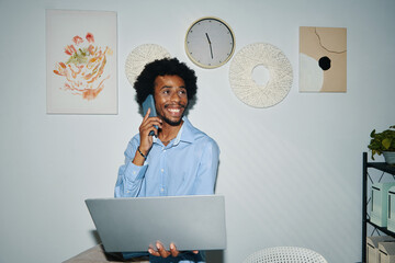 Portrait of excited Black entrepreneur talking on phone