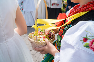 Girls in traditional Polish costumes with baskets of flower petals during Corpus Christi...