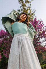 portrait of a happy girl. urban style and fashion. A young brunette smiles happily while walking in a city garden. Young stylish girl in a shirt.