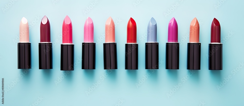 Poster top view of various stunning lipsticks on a light blue backdrop perfect for adding text. copy space 