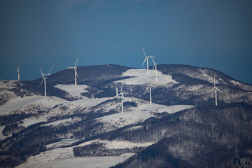 A distant view of a wind turbine on a snow-capped mountain peak of Taegi Mountain in Hoengseong...