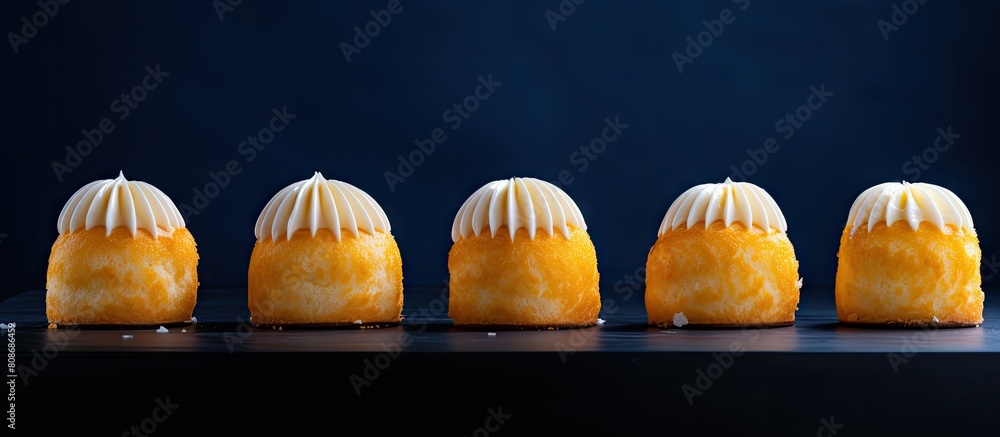 Poster a row of yellow lemon round baked macaroon cakes on a dark blue background with dessert stands close