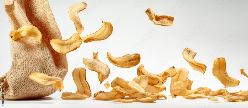 Poster copy space image of dried banana slices falling from a sack bag against a white background