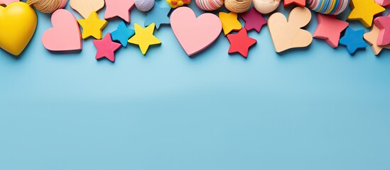 Top view of a colorful flat lay with eco friendly wooden toys including heart shaped rattles and star shaped toys placed on an isolated pink blue and yellow background This copy space image serves as