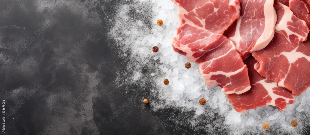 Poster A top down view of sliced raw pork meat on a gray stone table with ample space for text in the image background