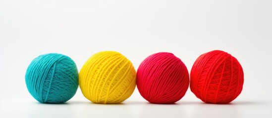 A plain white background with copy space hosts three vibrant balls of woolen yarn