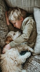 Overhead view of boy and fluffy dog sleeping on sofa together.