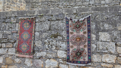 Antique oriental carpets with patterns made of natural wool. Antique carpets on a stone wall in an...