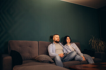 a man and a woman watch an elevator on the couch at home