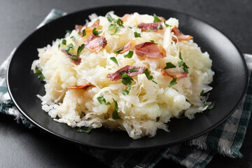 Slovak potato dumplings halusky with steamed sauerkraut and bacon on black background. Close up