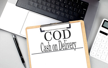 COD -CASH ON DELIVERY word on clipboard on laptop with calculator and pen