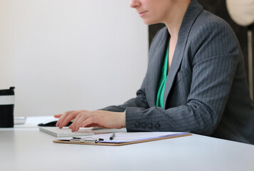 Close up of a young woman working in office at table, blurry background