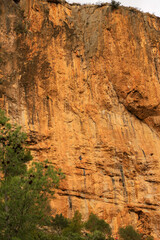Large reddish rock wall with climbing routes for mountaineers in the city of Chulilla,Valencia,Spain