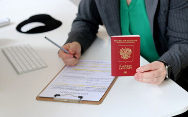 Top view close up of a woman filling out visa application documents with a Russian passport